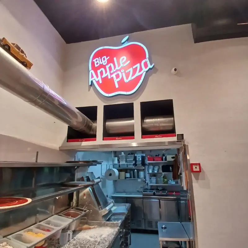 Rótulo de marca Big Apple Pizza en cocina interior — SignWorks