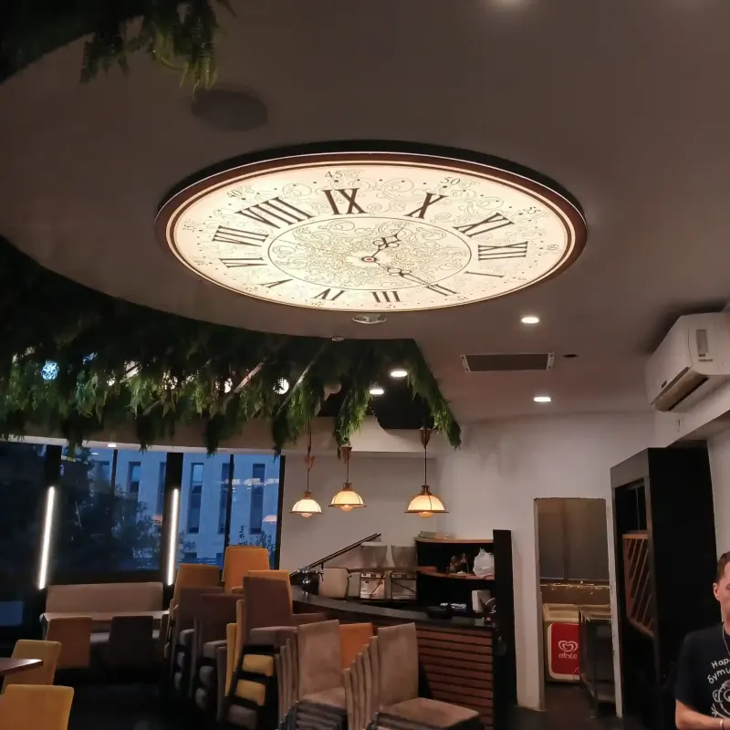 Reloj decorativo de techo con números romanos en interior de café — SignWorks