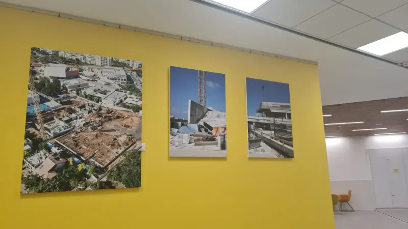 Fotografías de obra de construcción exhibidas en pared amarilla — SignWorks