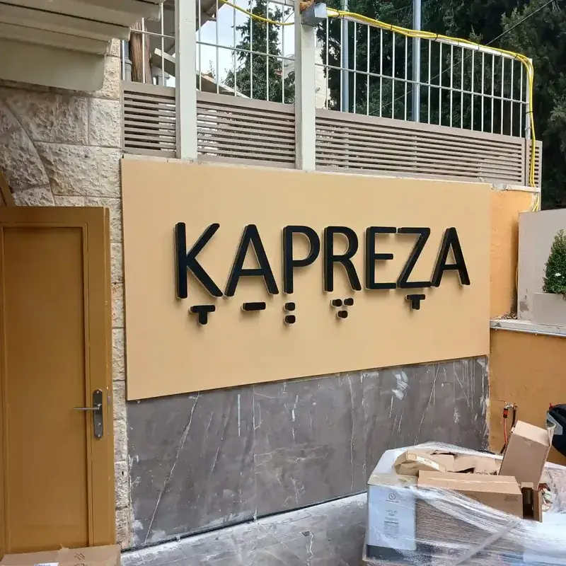 Rótulo Kapreza montado en pared exterior beige — SignWorks