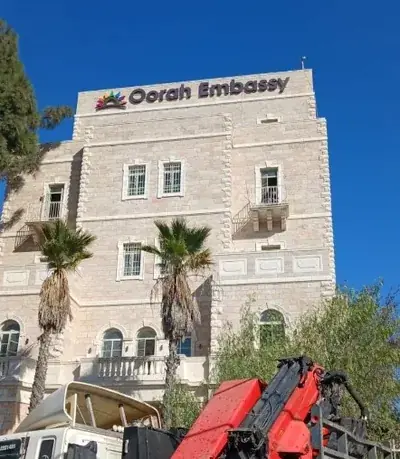 Rótulo iluminado Oorah Embassy con logo en color en edificio alto de piedra — SignWorks