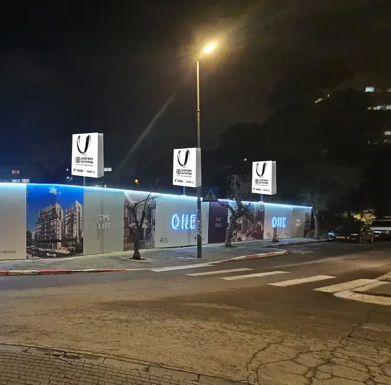 Valla de construcción Paran Prime con letras iluminadas y objetos impresos en postes de hierro — SignWorks