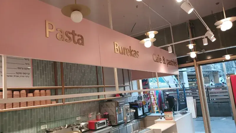 Fachada de cafetería con letras doradas dimensionales y rótulo comercial iluminado