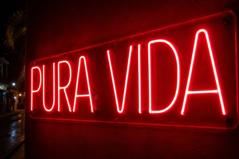 Rótulo de neón LED rojo Pura Vida encendido sobre una pared exterior oscura de noche en Costa Rica